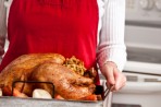 Cook holding tray with cooked turkey on it