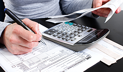Woman calculating tax rebate using a calculator.