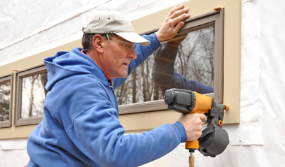contractor using a nail gun to seal a window