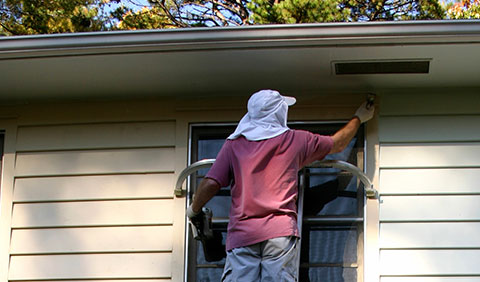 Man on ladder air sealing a window